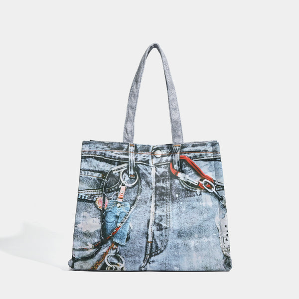 Large open-top tote bag with printed denim jeans graphic in faded blue-grey, dual flat shoulder straps and rivet hardware
