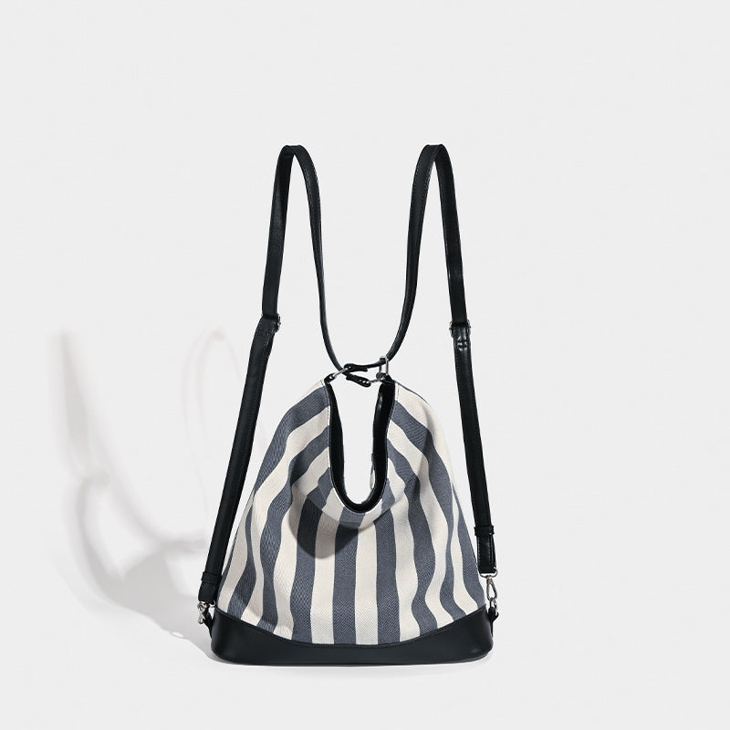 Blue and white vertical stripe canvas convertible tote backpack with leather-look trim and silver-tone hardware, detail view