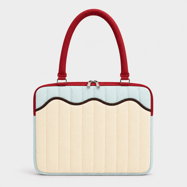 Quilted colorblock handbag with wavy scalloped front panel, padded arched top handles, and dual zip closure, front view