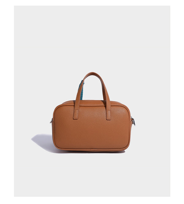 Structured pebbled leather-look Boston bowling bag in tan with blue detachable round mini pouch, dual top handles, and