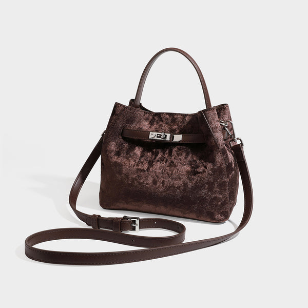 Small structured bucket satchel in embossed velvet-texture fabric with silver turn-lock hardware, rounded top handle, and