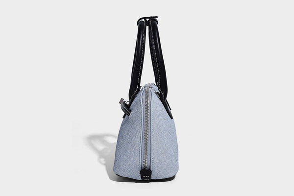 Compact structured satchel in light blue denim-look fabric with black leather-look trim, silver turn-lock closure, rolled