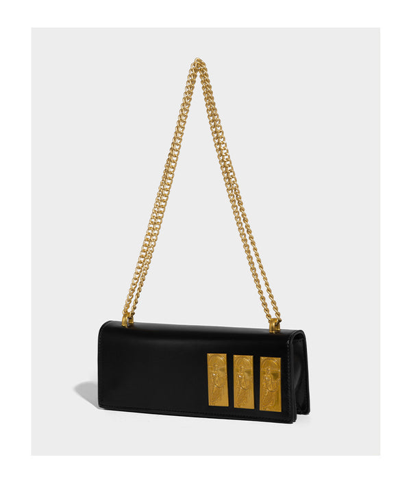 Structured rectangular crossbody bag with glossy finish, three vertical gold-tone embossed plaques, and gold chain strap
