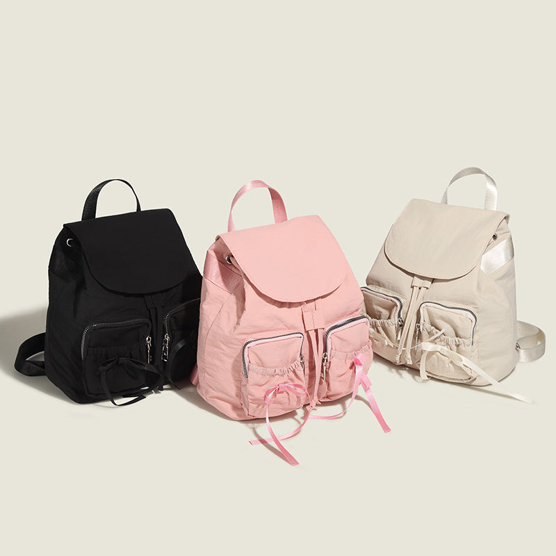 Soft matte nylon drawstring backpack with ruched bow-detail front zip pockets, top carry handle, and silver-tone hardware