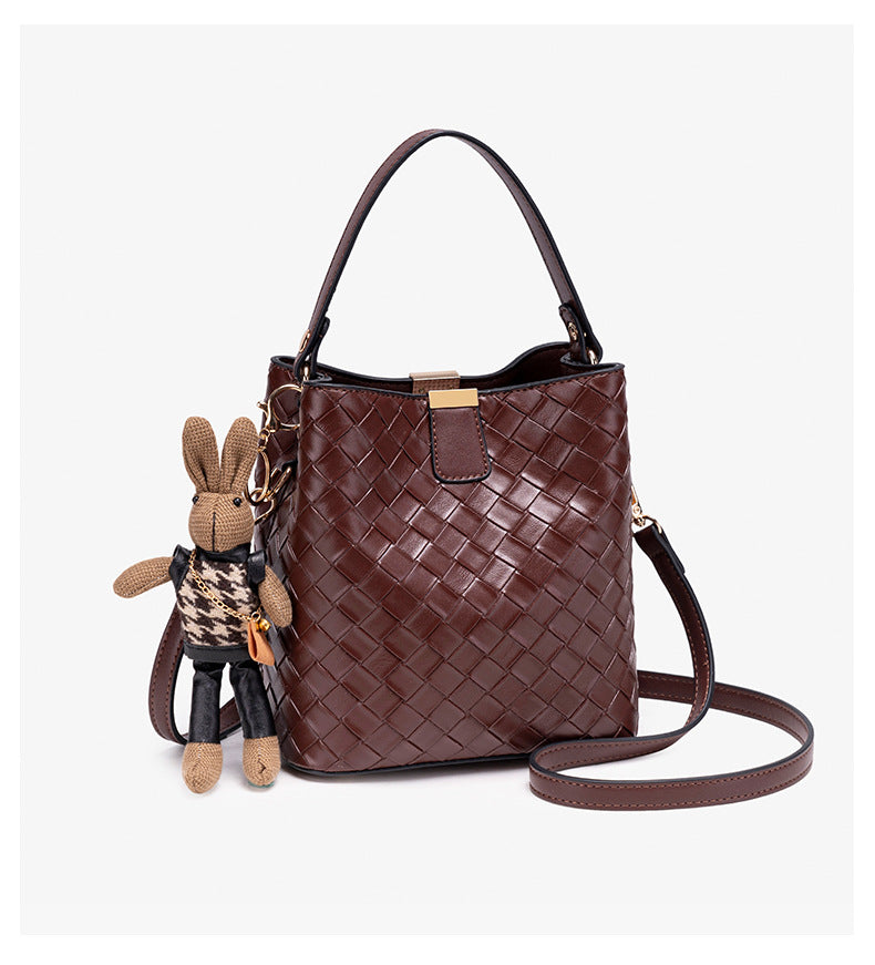 Brown woven-emboss leather-look bucket bag with short top handle, detachable crossbody strap, gold-tone hardware, and rabbit