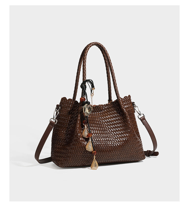 Strukturierter, glänzend geflochtener Shopper mit Muschelkantenabschluss am oberen Rand, geflochtenen Tragegriffen, abnehmbarem Crossbody-Riemen und Perlenquaste