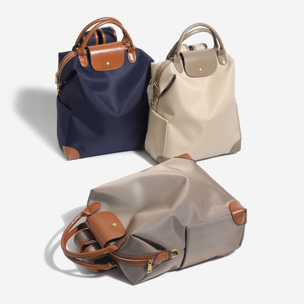 Large matte nylon backpack handbag with cognac leather-look trim, snap flap, and gold-tone hardware, front view