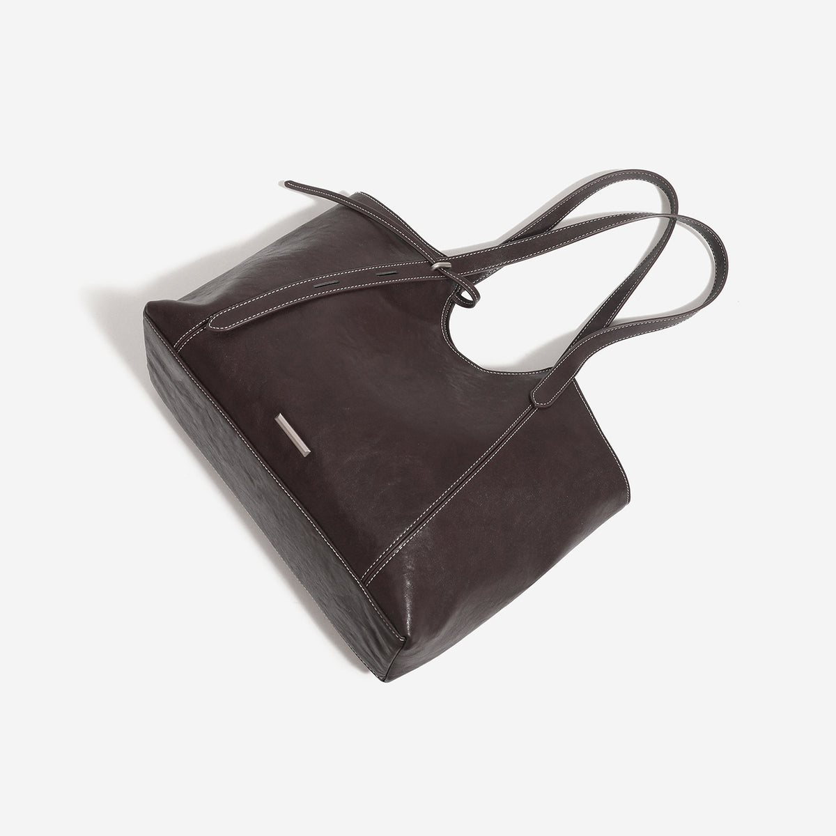 Strukturierte Tote-Tasche in Lederoptik mit zwei langen Schulterriemen, Bindebanddetail auf der Vorderseite und kontrastierenden weißen Steppnähten, Detailansicht