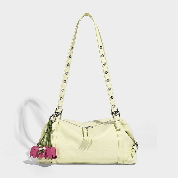 Pale yellow leather-look barrel bag with silver grommet-studded shoulder straps, top zip closure, and pink tulip floral