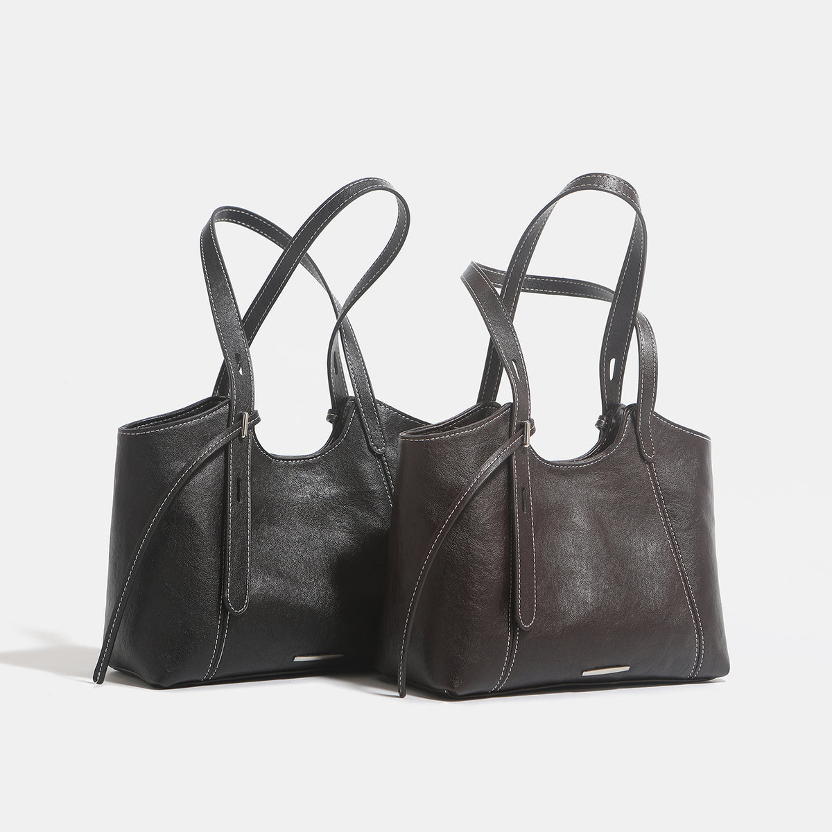 Structured leather-look tote shoulder bag with double crossed straps, contrast topstitching, and metal bar hardware, detail