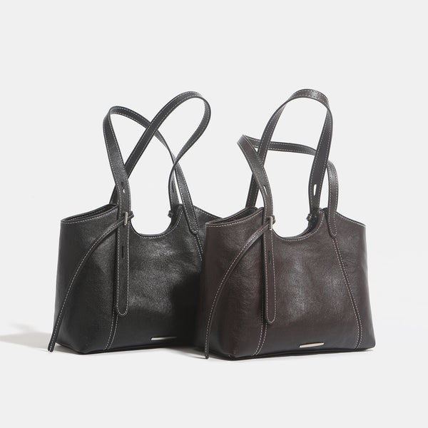 Structured leather-look tote shoulder bag with double crossed straps, contrast topstitching, and metal bar hardware, detail