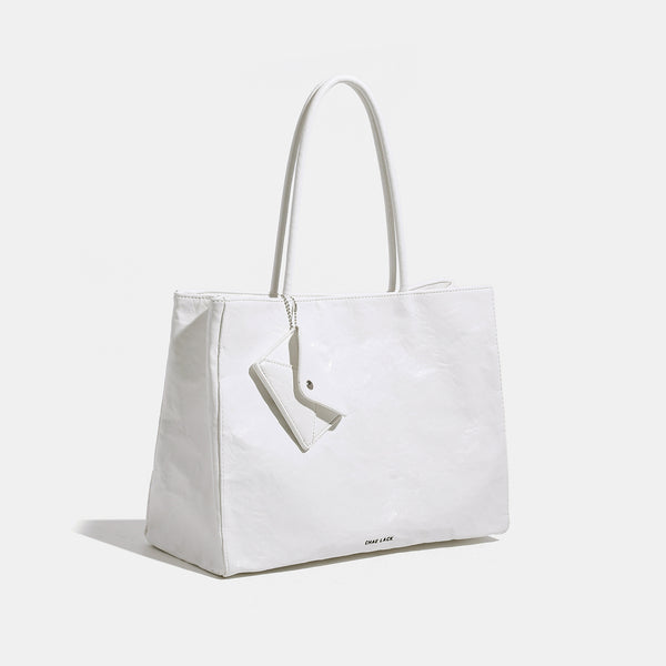 Structured rectangular crinkle leather-look tote bag with long rounded handles, zip top, and envelope-style hanging tag