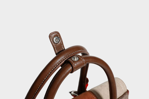 Structured color-block satchel bag in brown, rust, beige, and taupe suede-look panels with white topstitching, front buckle