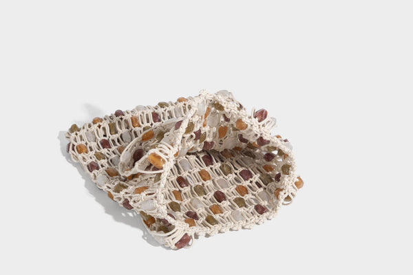 Cream macramé open-weave tote bag with multicolor amber olive and translucent bead accents and woven shoulder straps, detail