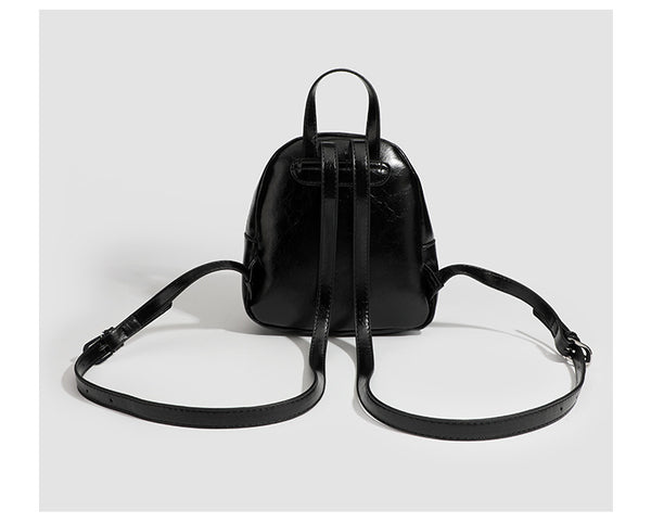 Kompakte, abgerundete Mini-Rucksackhandtasche mit glänzender Lederoptik, Reißverschluss oben, Fronttasche, Tragegriff oben und Detailansicht