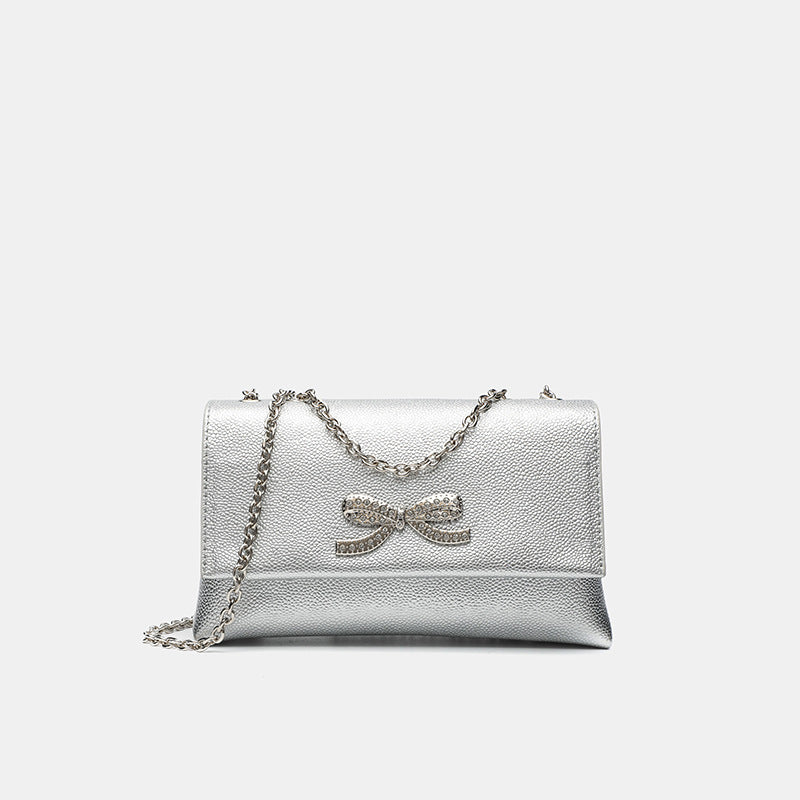 Structured rectangular flap crossbody bag with rhinestone bow and silver chain strap in pebbled finish, detail view 8