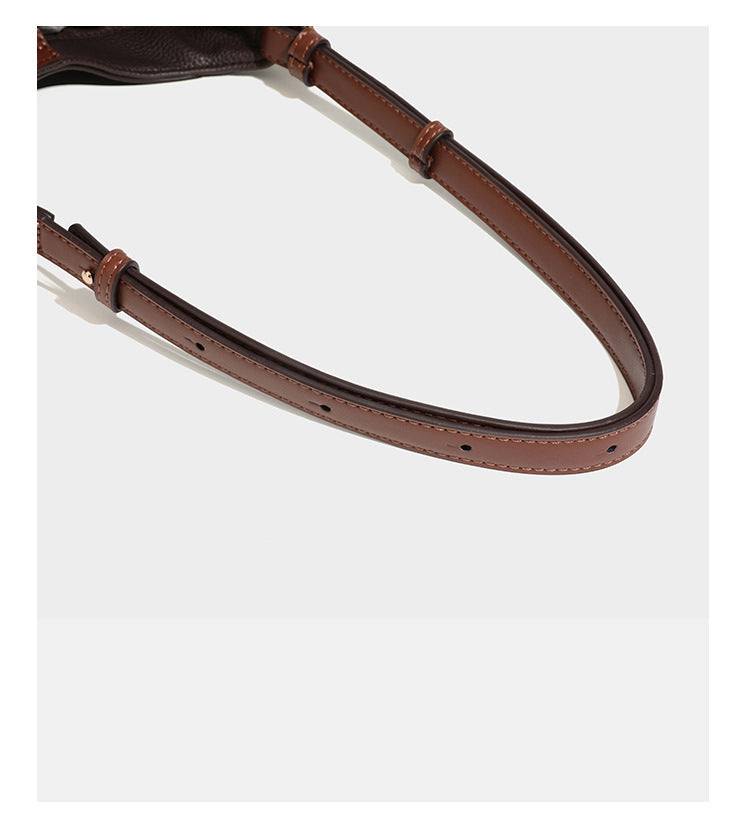 Hobo-Schultertasche in dunklem Espresso mit genarbter Oberfläche, warmen cognacfarbenen Details, verstellbarem schmalem Riemen, goldfarbenen Ringbeschlägen und geknotetem