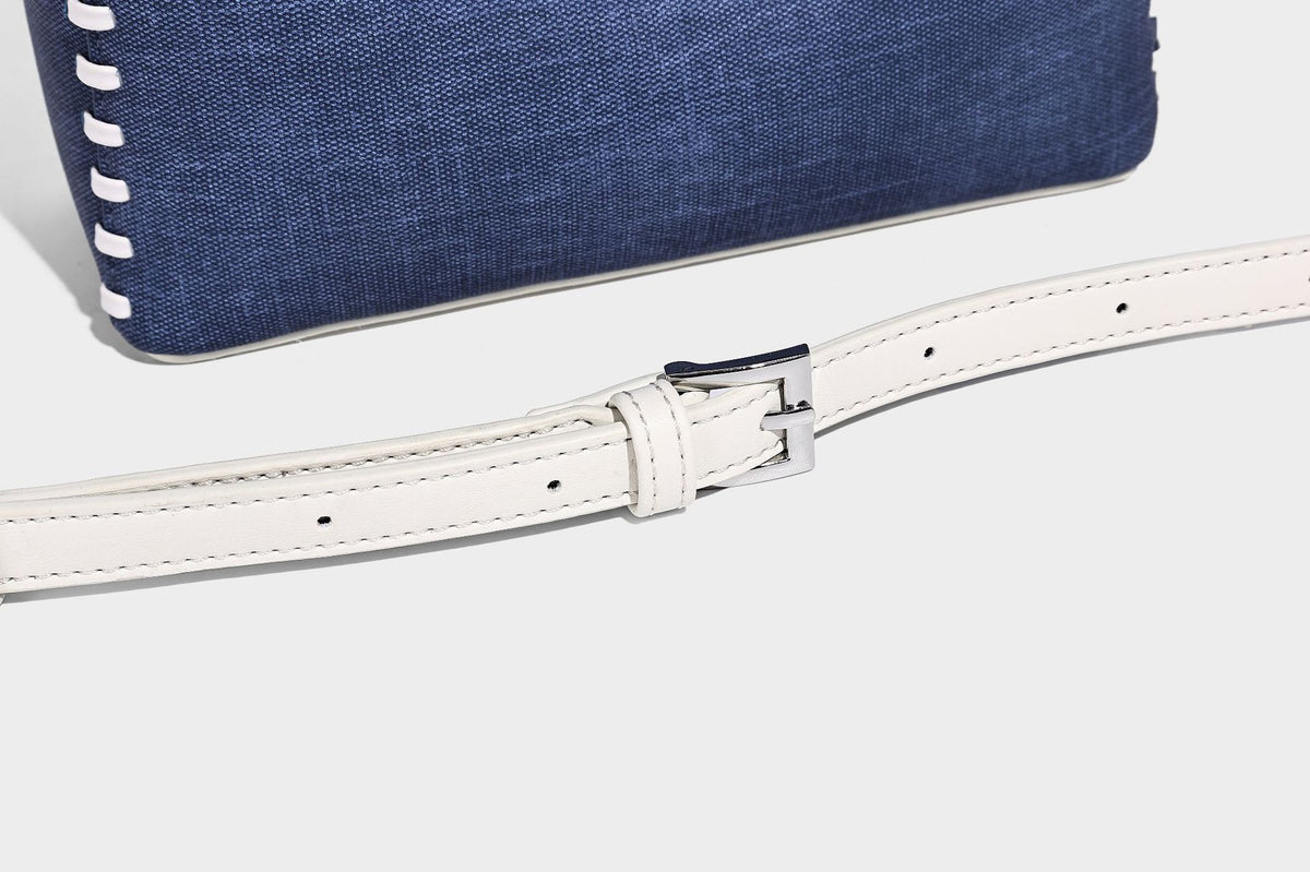 Formstabile Beuteltasche aus Denim mit weißem Zierstich-Besatz, silberfarbenem Drehverschluss, kurzen Henkeln und einem langen verstellbaren