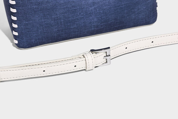 Formstabile Beuteltasche aus Denim mit weißem Zierstich-Besatz, silberfarbenem Drehverschluss, kurzen Henkeln und einem langen verstellbaren