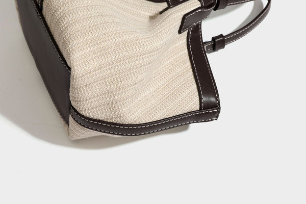 Cremefarbene geflochtene Tote-Bag mit dunkelbraunen Besätzen in Lederoptik, kontrastierenden weißen Nähten, zwei oberen Henkeln und abnehmbarem Schulter