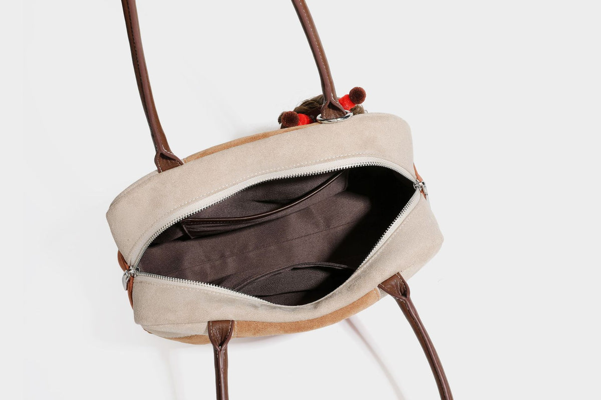 Boxy patchwork suede-look shoulder tote in tan, beige, rust, and brown panels with double brown straps and hanging doll