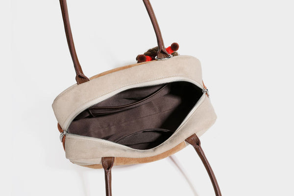 Boxy patchwork suede-look shoulder tote in tan, beige, rust, and brown panels with double brown straps and hanging doll