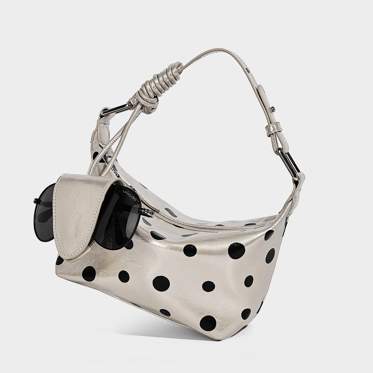 Schultertasche in glänzender Lederoptik mit Tupfenmuster, befestigtem Mini-Fronttäschchen, Reißverschluss oben und verstellbarem Riemen, Detailansicht