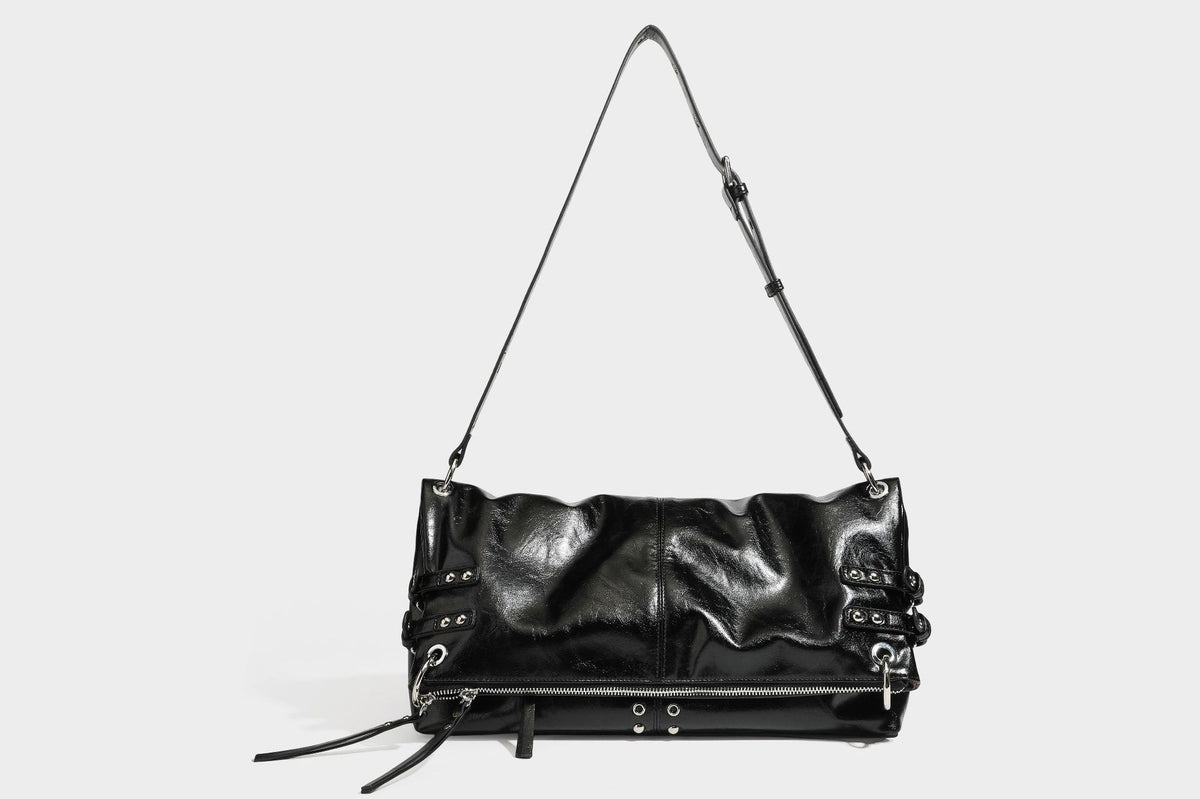 Black glossy leather-look slouchy shoulder bag with silver stud and eyelet hardware, top zip closure, front zip pocket, and