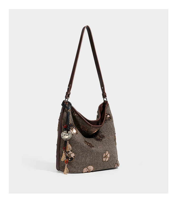 Lässig fallende Hobo-Schultertasche aus anthrazitfarbenem Webstoff mit floraler Stickerei aus silberfarbenen Pailletten, schwarzem Besatz in Lederoptik und langem