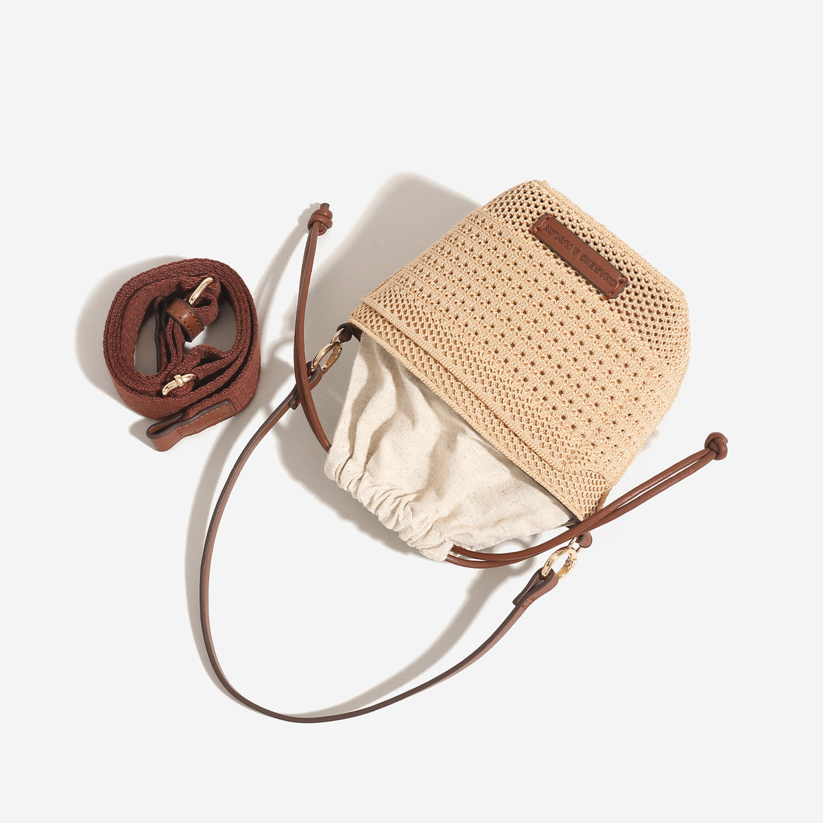 Compact openwork woven bucket bag with gathered cream drawstring liner, leather-look brown trim and cords, and gold-tone