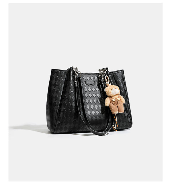 Black diamond-quilted leather-look tote bag with silver chain-ring shoulder straps and plush bear charm pendant, detail view