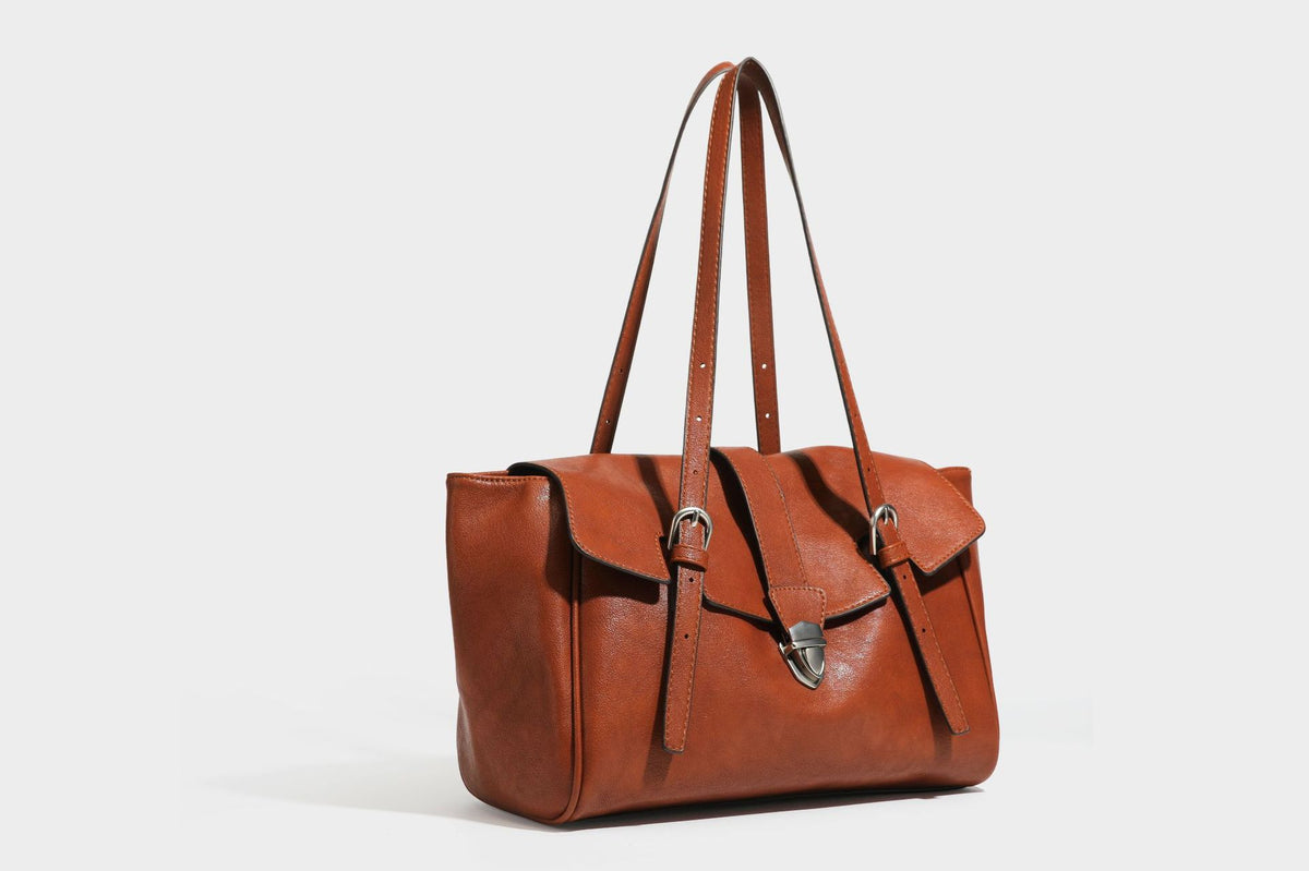 Large structured vintage-style tote bag with flap-front turn-lock closure, twin buckle straps, and double shoulder handles