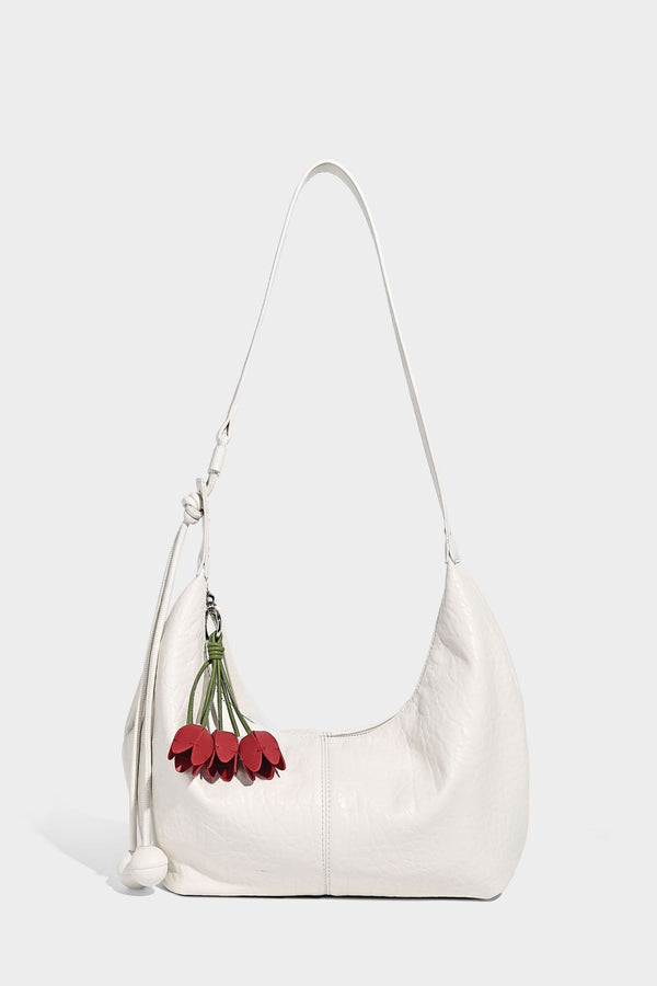 Slouchy crescent half-moon shoulder bag in pink pebbled textured finish with floral charm and knotted side detail, detail