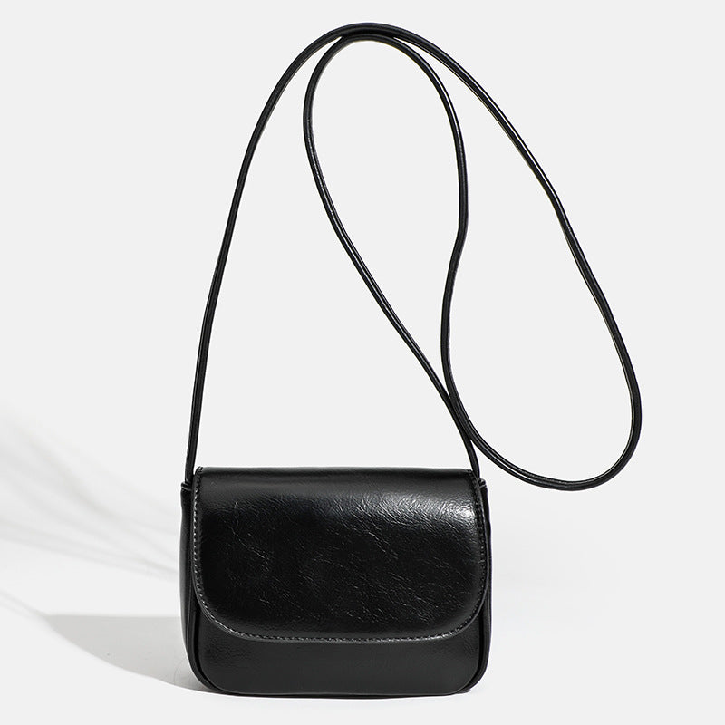 Compact rounded rectangular flap crossbody bag with glossy leather-look finish and long shoulder strap, detail view 7