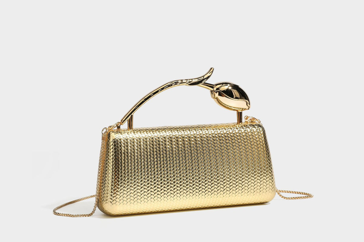 Structured rectangular metallic woven clutch bag with sculptural gold-tone leaf top handle and detachable chain strap, detail