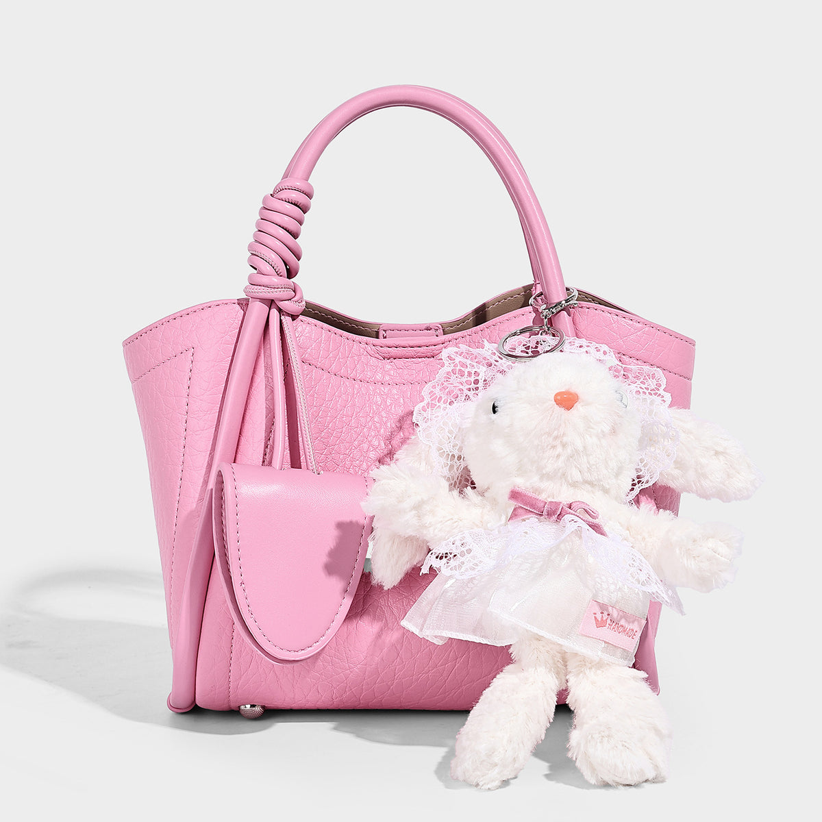 Structured mini tote bag in pebbled leather-look finish with knotted top handles, front flap pocket, and detachable shoulder