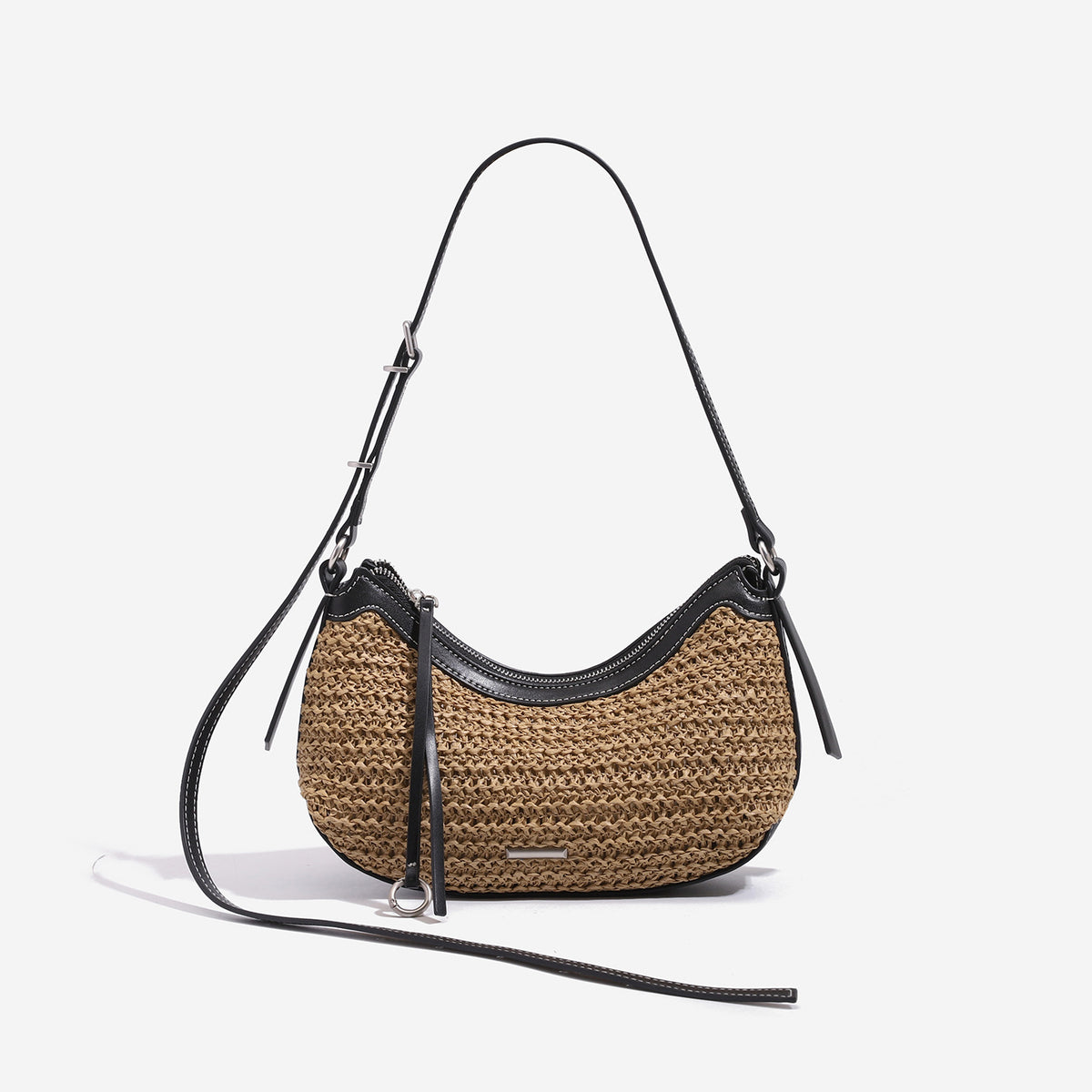 Tan woven straw half-moon shoulder bag with black leather-look trim, zip closure, tassel pull, and adjustable crossbody