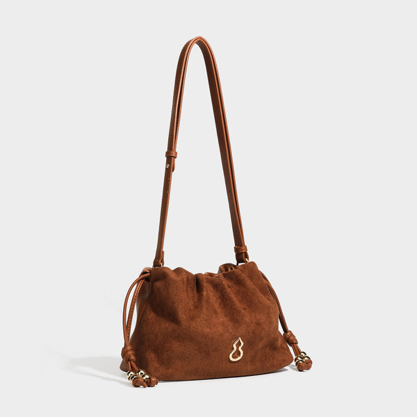 Suede-look drawstring shoulder bag in brown with smooth trim, knotted bead drawstring closure, slim adjustable strap, and