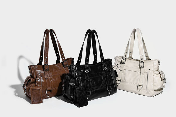 Glossy structured black tote shoulder bag with silver buckle hardware, zip pockets, dual top handles, and detachable, detail