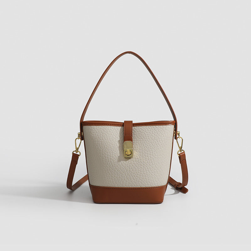 Formstabile zweifarbige Bucket Bag aus genarbtem Material mit goldfarbenem Drehverschluss und cognacfarbenem Besatz in Lederoptik, Vorderansicht