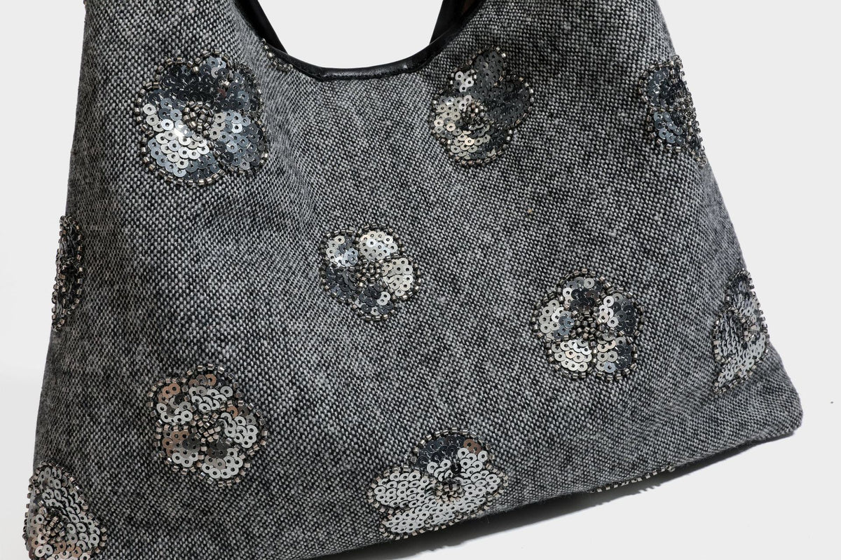 Lässig fallende, trapezförmige Schulter-Tote in Anthrazitgrau mit floralen Paillettenmotiven in Silber, Riemen in Lederoptik und herabhängendem Perlenbesatz