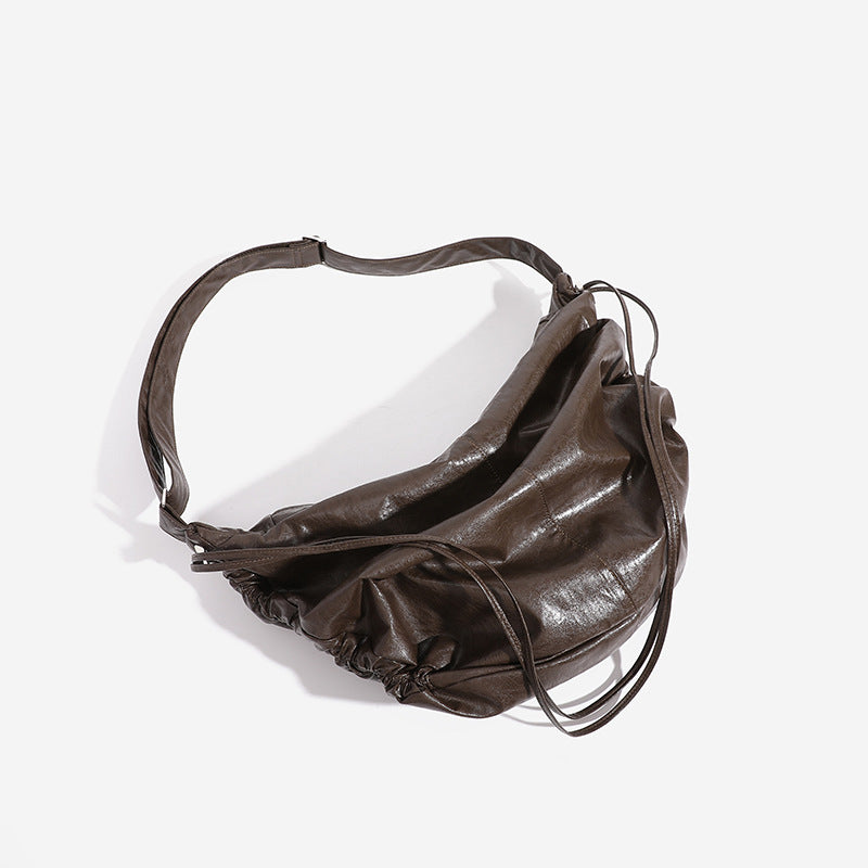 Oversized slouchy hobo shoulder bag with glossy crinkled leather-look finish, drawstring gathered sides, and silver-tone