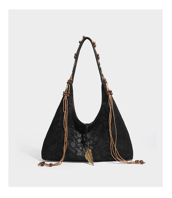Slouchy boho hobo shoulder bag in embossed brown suede-look finish with beaded strap, cord tassels, and brass-tone leaf