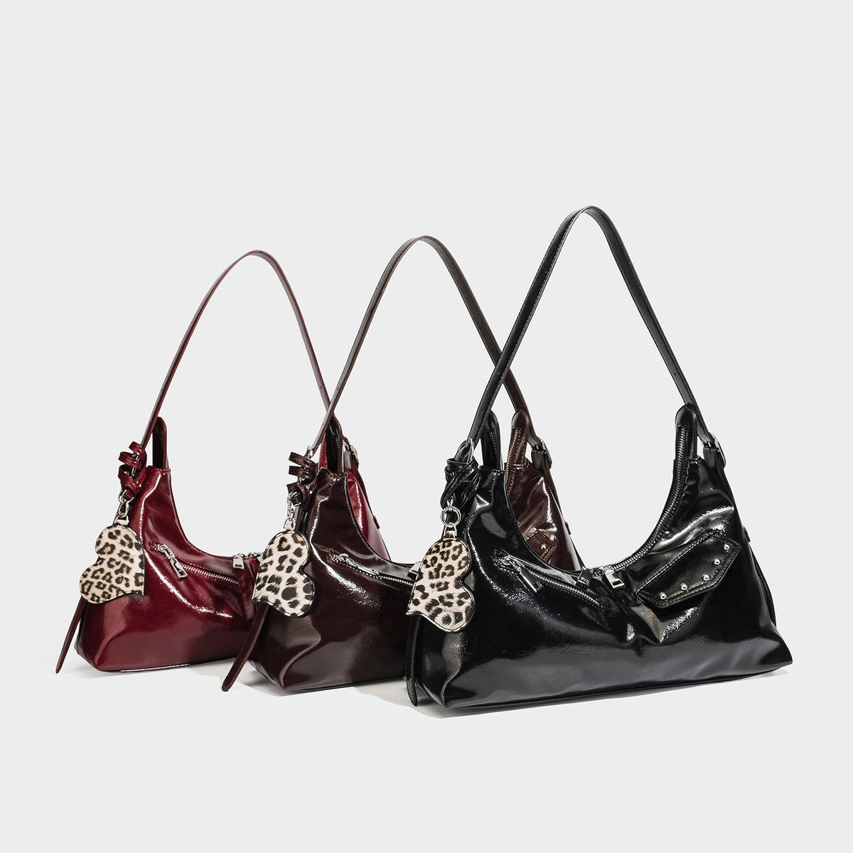 Glossy dark brown hobo shoulder bag with slim strap, front zip pocket, stud detail, and detachable leopard-print heart charm