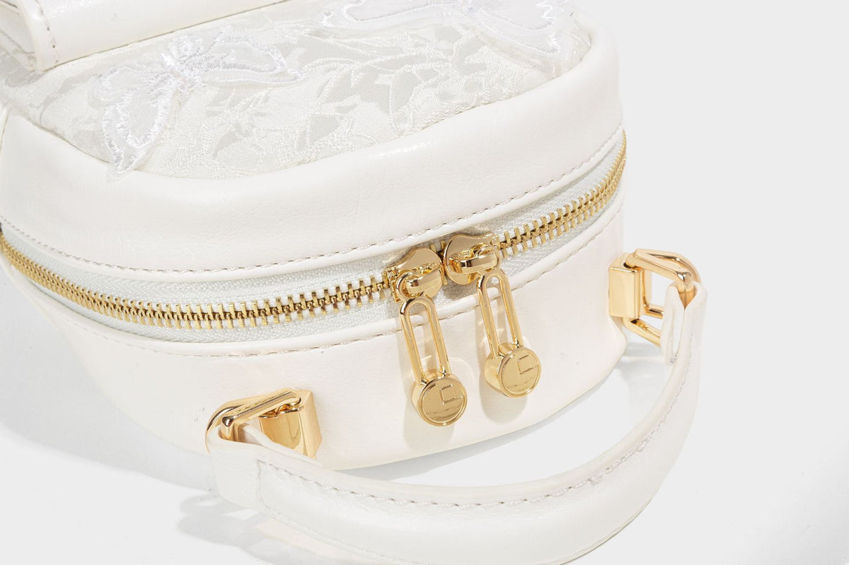 Structured mini backpack handbag with butterfly embroidery, gold-tone chain strap, and turn-lock front flap pocket, detail