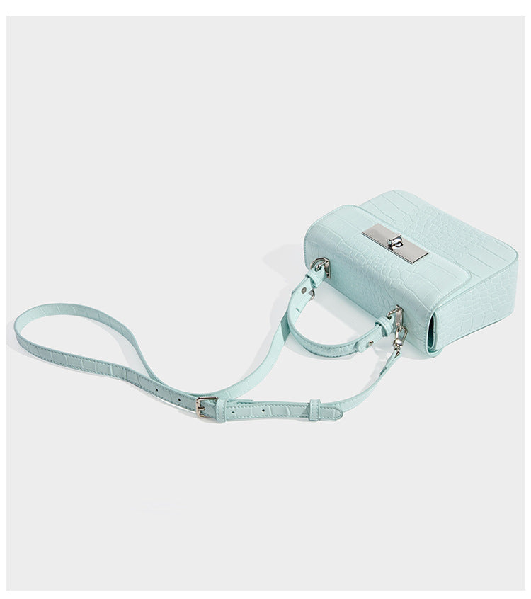 Small structured rectangular satchel with glossy crocodile-embossed finish, arched top handle, front flap, and silver-tone