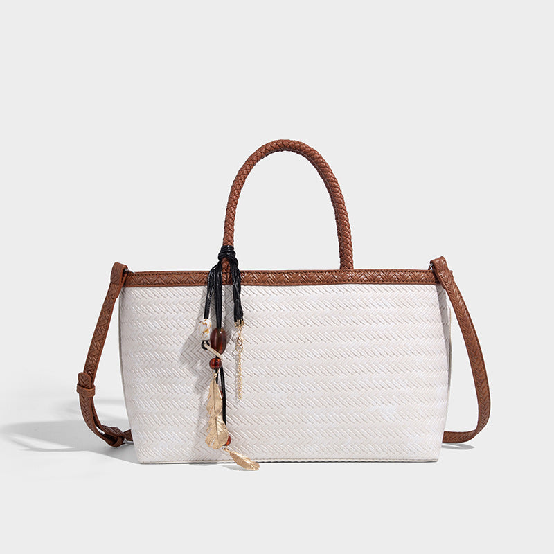 Structured woven-texture tote bag with brown braided top handles, decorative tassel charm, and detachable shoulder strap
