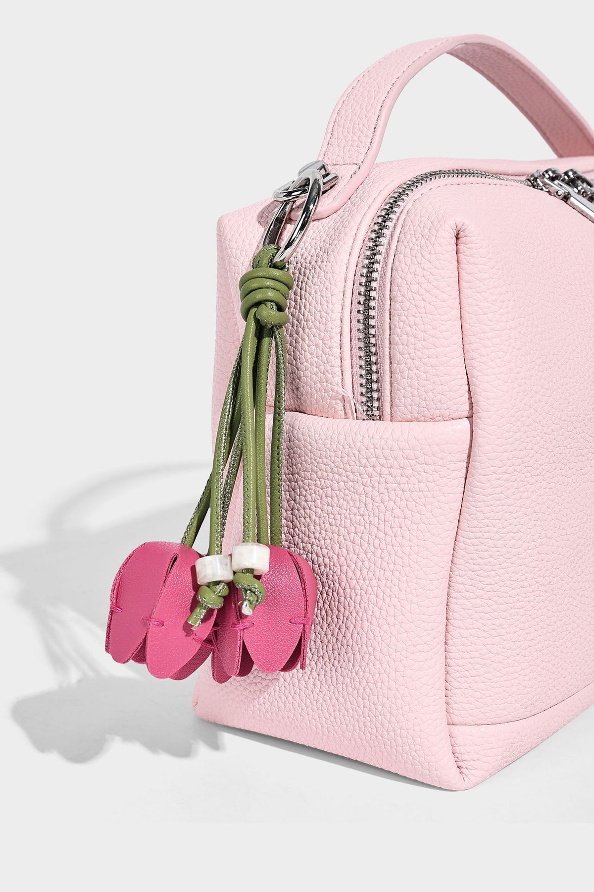 Kleine strukturierte Crossbody-Tasche mit Tragegriff aus genarbtem Material, Reißverschluss, silberfarbenen Beschlägen und optionalem Quastenanhänger
