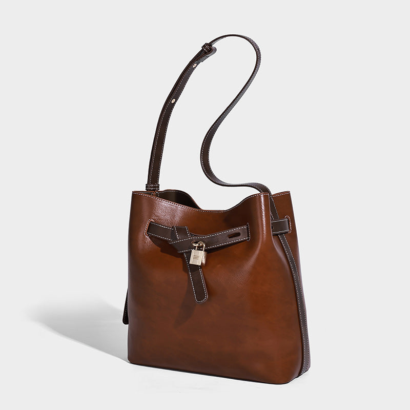 Glossy leather-look bucket shoulder bag with padlock strap detail and adjustable long strap, front view