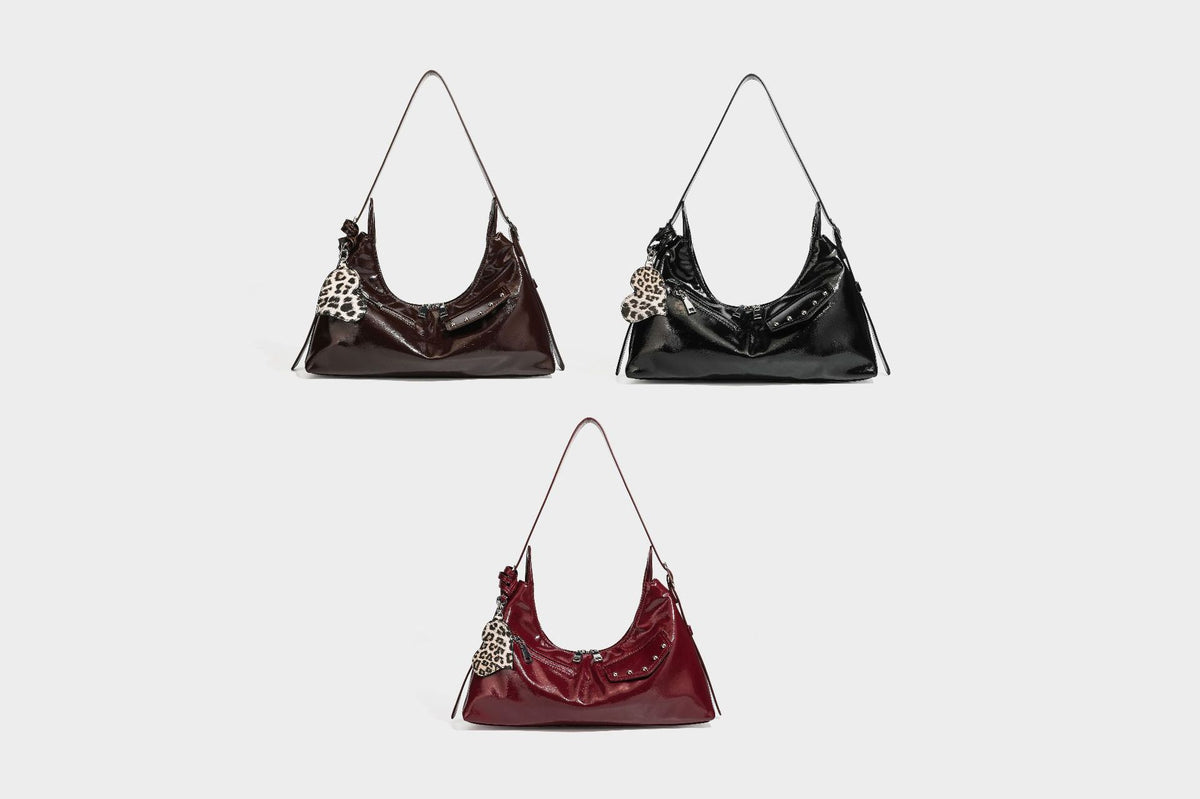 Glossy dark brown hobo shoulder bag with slim strap, front zip pocket, stud detail, and detachable leopard-print heart charm